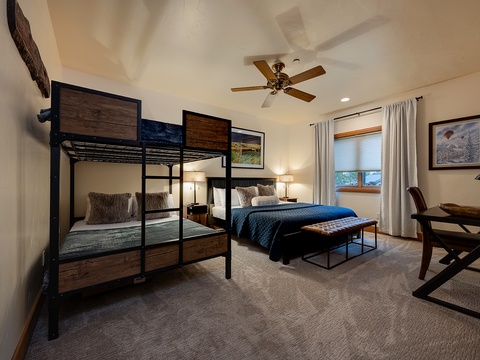 Your spacious bedroom offers flexible sleeping arrangements with a sturdy bunk bed and a plush queen bed, all beneath a gentle ceiling fan and soft natural light streaming through your window.