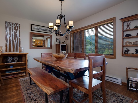 Gather around the handcrafted wood dining table with mountain views, where your group can share meals and stories in this warm, cabin-inspired space filled with rustic charm.