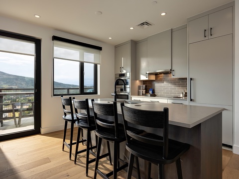 Gather at the sleek kitchen island where stunning mountain views frame your morning coffee. Stylish bar seating invites conversation while you cook in this modern, light-filled space that flows effortlessly to your private balcony.
