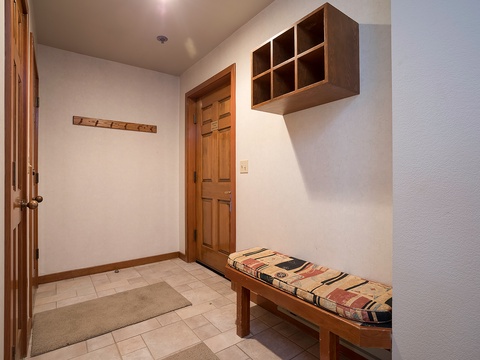 Step into your private entryway with warm wood accents, handy cubby storage above, and a cozy bench for settling in after a day of mountain adventures.