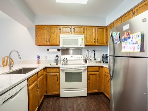 Your fully equipped kitchen awaits with everything you need—gleaming stainless appliances, ample counter space, and warm wood cabinetry. Picture yourself whipping up delicious meals or your morning coffee in this bright, skylit space.