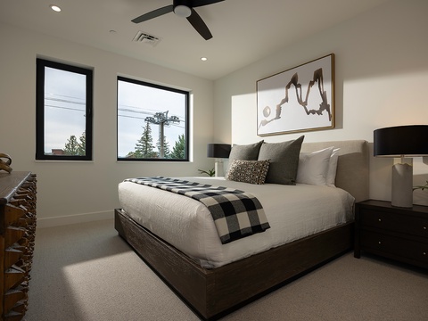 Drift off in this serene bedroom, where natural light pours through large windows and a cozy plaid throw awaits at the foot of your plush bed. The ceiling fan keeps the air fresh while you unwind in modern comfort.