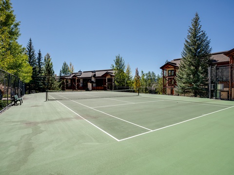 Private tennis court with mountain and forest backdrop, offering outdoor recreation during your mountain getaway.