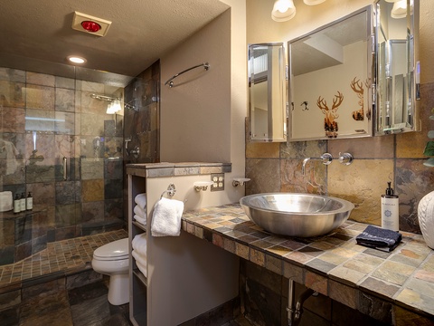 Step into your private spa-like retreat with a walk-in shower, rustic-elegant tilework, and a gleaming vessel sink—your peaceful mountain sanctuary awaits.