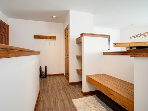 Step into your private mudroom—custom wood shelves and hooks keep your gear organized, while warm tones and thoughtful design make arriving home feel effortless.