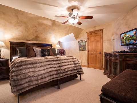 Sink into the plush faux-fur bedding and enjoy your favorite shows on the flat-screen TV in this cozy, warmly-lit bedroom with rustic elegance and vaulted ceilings.