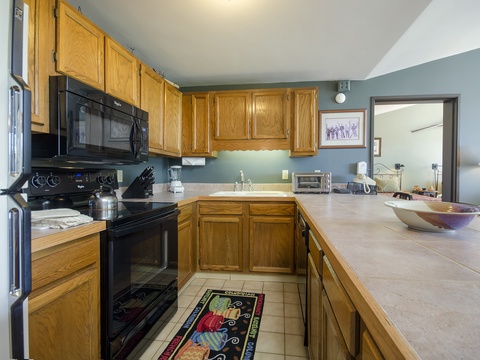 Your vacation kitchen comes fully equipped with modern appliances, warm wood cabinetry, and generous counter space for prepping meals or sharing morning coffee together.
