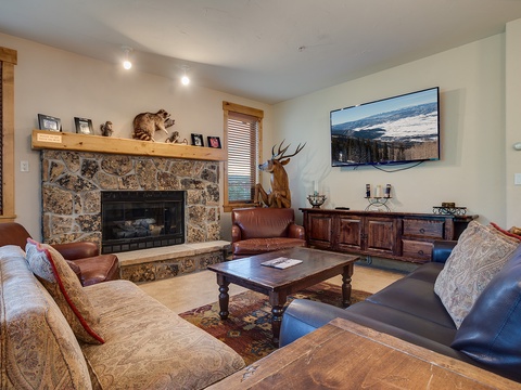Cozy mountain living room with stone fireplace, plush seating, and rustic décor—your perfect retreat after a day of adventure.
