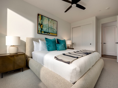 Drift into restful sleep in your serene bedroom, where soft natural light warms crisp linens and plush teal pillows invite you to unwind beneath the gentle ceiling fan.