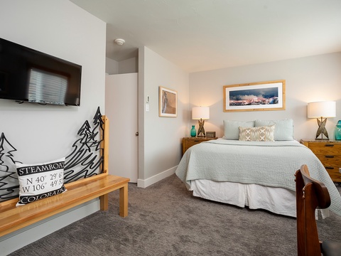 Your peaceful mountain retreat awaits with plush bedding, modern entertainment, and thoughtful touches like bedside lamps and local artwork—perfect for unwinding after a day of adventure.