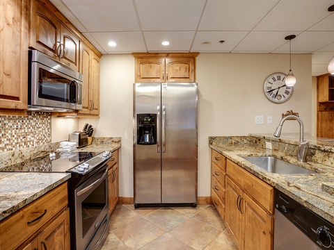 Your fully equipped kitchen features warm wood cabinetry, granite countertops, and stainless steel appliances, ready for preparing memorable meals during your stay.
