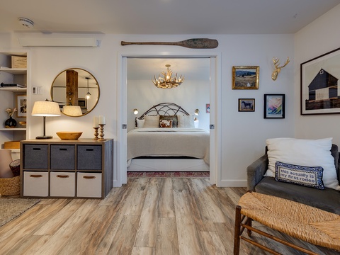 Cozy living space flows seamlessly into the bedroom, featuring curated artwork, warm lighting, and a vintage oar that adds rustic charm to your mountain retreat.