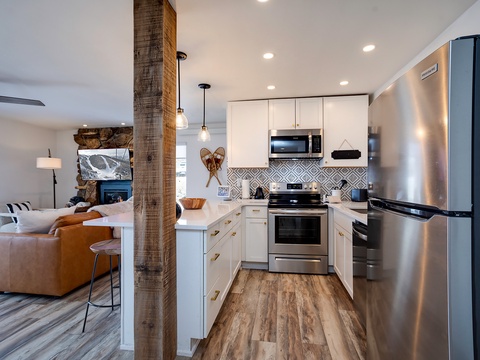 Step into your fully-equipped kitchen with modern stainless steel appliances, crisp white cabinetry, and an open layout that flows into the cozy living area—perfect for whipping up meals while staying connected to your group.