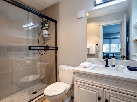 Your private bathroom features a walk-in shower, elegant marble countertops, fresh towels, and natural light from the skylight—perfectly designed for your comfort and relaxation.