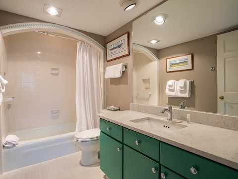 Your private bathroom features a soaking tub, elegant marble countertops, plush towels, and charming artwork—a serene retreat designed for your comfort and relaxation.