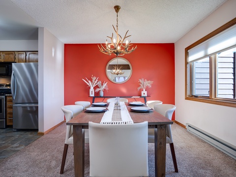 Gather around this rustic dining table beneath a stunning antler chandelier. Your meals become mountain memories with bold red décor, natural light streaming through windows, and seating for six ready for laughter and connection.
