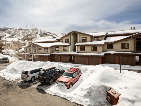 Snow-covered multi-unit property nestled at the base of ski slopes, offering convenient parking and mountain access for winter getaways.