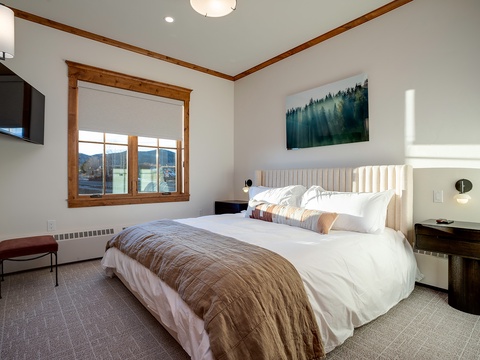 Sink into plush bedding with mountain views just beyond your window, where warm wood tones and peaceful forest artwork create your perfect retreat after a day of adventure.