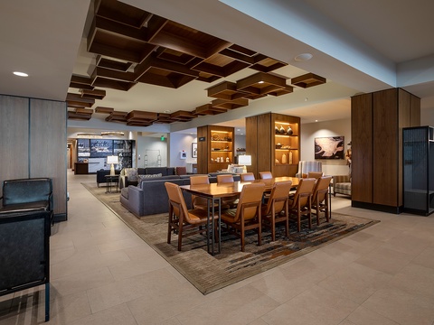 Modern lobby with a striking geometric wood ceiling, plush seating, and a large communal table perfect for gathering with fellow travelers.