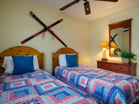 Cozy twin bedroom with handmade quilts, rustic ski décor, and warm lighting—perfect for your mountain getaway with friends or family.