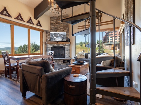 Unwind in your mountain-view living room where rustic wood beams meet modern comfort. The stone fireplace and cozy seating invite you to relax after a day exploring nearby trails.