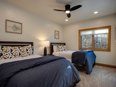 Wake up to peaceful forest views from your cozy bedroom, where two plush beds and modern touches await your restful getaway.