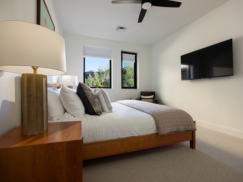 Drift off in this serene bedroom where soft linens meet modern desert design. Natural light streams through your windows, framing peaceful views, while the ceiling fan keeps you cool and comfortable throughout your stay.