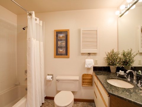 Your private bathroom features a full tub-shower combo, granite countertops, and thoughtful touches like fresh greenery to make your stay feel like home.