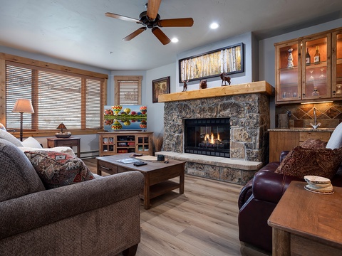 Unwind in your cozy living room with plush seating, a warm stone fireplace, and charming mountain-inspired décor that invites you to relax and feel at home.
