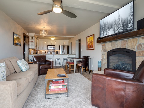 Unwind in your cozy living space with a stone fireplace, comfortable seating, and a fully equipped kitchen. Perfect for relaxing evenings after exploring the slopes.
