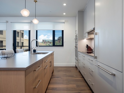 Step into a bright, modern kitchen with sleek cabinetry, a spacious island, and warm wood floors—your perfect spot to whip up memorable meals during your getaway.