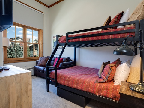 Cozy bunk beds wrapped in warm reds and oranges create a perfect retreat for your group, with mountain views just outside your window.
