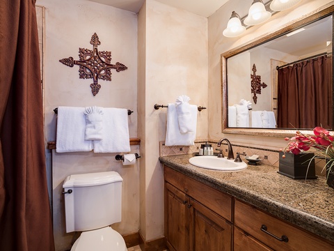 Step into your private bathroom where fluffy white towels and rustic charm welcome you. Warm wood tones, granite counters, and thoughtful touches like fresh flowers create a cozy retreat for unwinding.