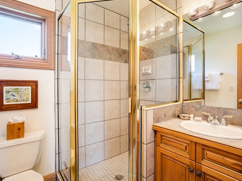 Step into your private bathroom featuring a tiled walk-in shower, warm wood cabinetry, and bright natural light—your own space to refresh and unwind.