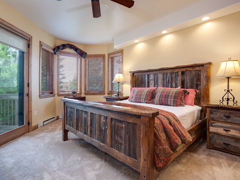 Drift into restful sleep in this inviting bedroom featuring a handcrafted rustic bed, warm ambient lighting, and your own private door to the outdoors for fresh mountain air.