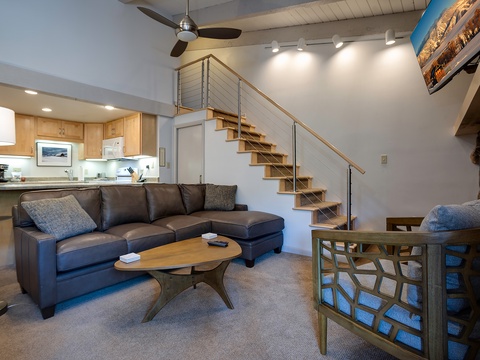 Relax in your bright, open living space with a modern sectional sofa, stylish coffee table, and fully equipped kitchen just steps away—perfect for unwinding after a day of adventure.