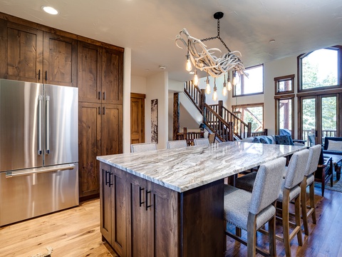 Gather around the spacious marble-topped island under a striking antler chandelier—your perfect spot for meals, morning coffee, or simply taking in the mountain views through expansive windows.