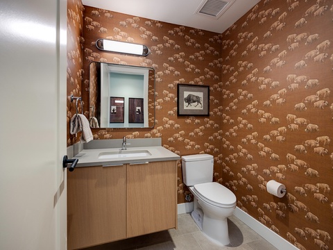 Freshen up in your charming bathroom featuring bold bison-patterned wallpaper, modern vanity, and whimsical Western décor that makes every visit memorable and fun.