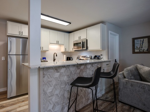 This stylish open-concept space features a fully equipped kitchen with modern appliances and a chic breakfast bar where you can enjoy your morning coffee.