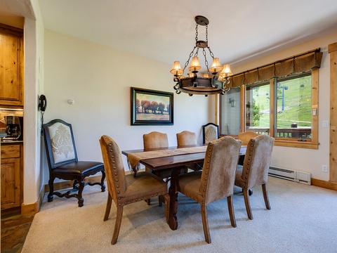 Gather around this handsome dining table where mountain views frame your meals and conversations linger long into the evening under the warm glow of rustic lighting.