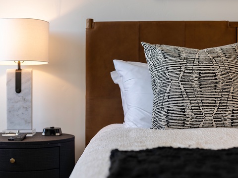 Sink into plush linens and settle in for the night—your peaceful retreat awaits with soft textures and warm lighting at your bedside.