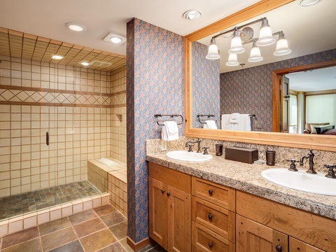 Step into your private spa retreat with double vanities, warm wood tones, and a spacious tiled walk-in shower that invites you to unwind after a day of adventure.