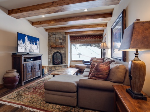 Unwind in your mountain retreat with vaulted wood-beam ceilings, a stone fireplace, and ski slope views—your perfect après-ski sanctuary awaits.