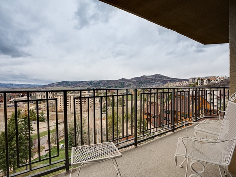 Aerial view capturing the property's elevated mountain setting and surrounding residential area with dramatic peaks on the horizon.