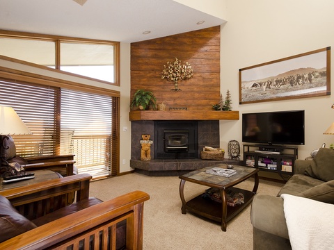 Gather in your cozy living room where mountain-rustic charm meets comfort—a wood-accented fireplace, plush seating, and entertainment center invite relaxing evenings after days on the slopes.