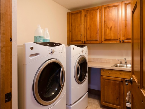 A well-appointed laundry room awaits with a full-size washer and dryer, utility sink, and ample cabinetry for your convenience during your stay.