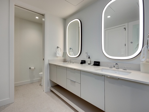 You'll love getting ready in this sleek, modern bathroom with its beautiful double vanity, backlit mirrors, and spa-like atmosphere that makes every morning feel luxurious.