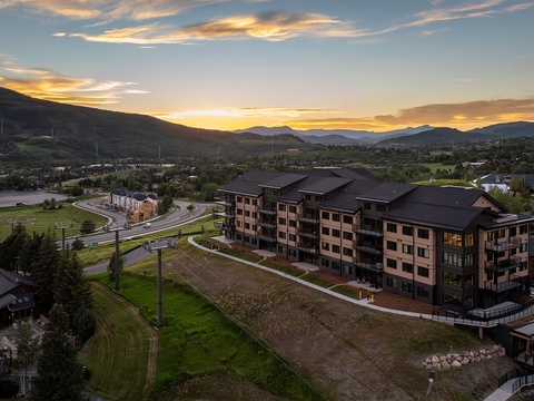Aerial view of the property nestled in a mountain valley at sunset, showcasing the surrounding natural landscape and peaceful neighborhood setting.