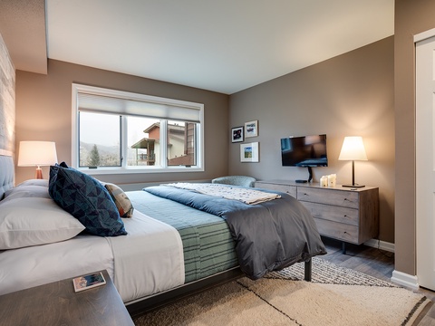 Sink into crisp linens and enjoy your favorite shows in this serene bedroom, where mountain views and modern comfort create the perfect retreat after a day of adventure.