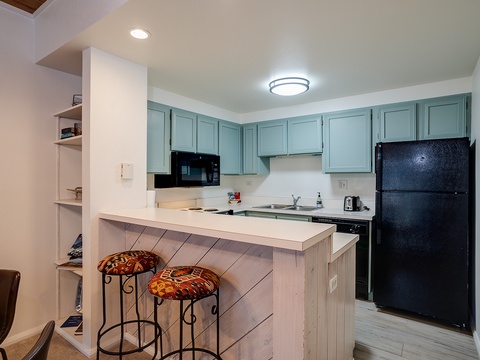 Your fully equipped kitchen awaits with stylish blue cabinetry, modern appliances, and a cozy breakfast bar—perfect for morning coffee or preparing your favorite meals.